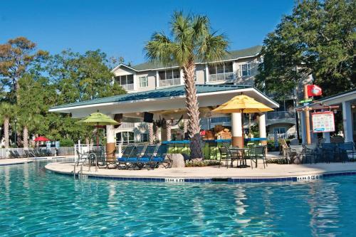 默特尔比奇Holiday Inn Club Vacations South Beach Resort的酒店前方的游泳池配有椅子和遮阳伞