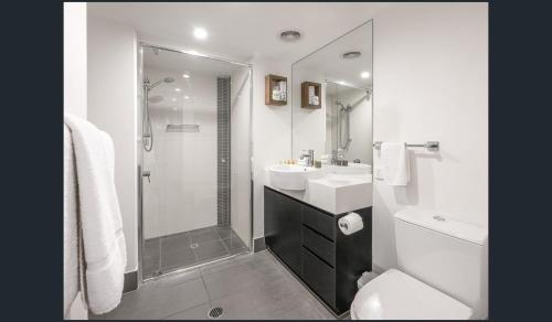 布里斯班Discover urban bliss in our 1-bedroom apartment! City views and cultural gems.的白色的浴室设有水槽和淋浴。