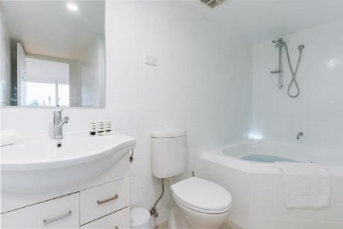 贝尔康嫩Lakeside 3-Bed Apartment with Jacuzzi的白色的浴室设有卫生间、水槽和浴缸。