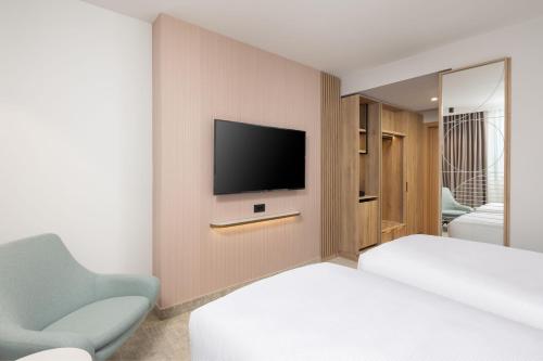 克卢日-纳波卡Courtyard by Marriott Cluj - Napoca Downtown的一间卧室配有一张床,墙上配有电视