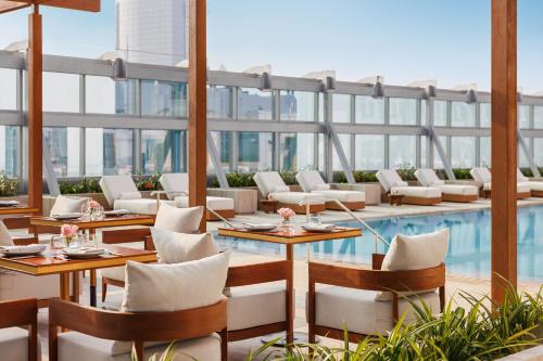 迪拜Jumeirah Living World Trade Centre Dubai的一间带游泳池和桌椅的餐厅