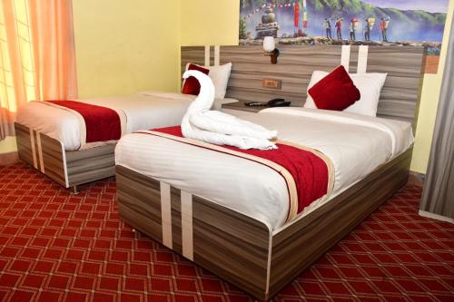 DhangadhiHotel Jiyan Hospitality Pvt. Ltd.的两张床铺,位于酒店客房内,配有天鹅