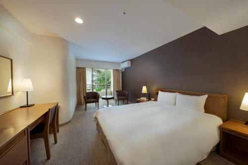 北中城村EM Wellness Kurashinohakko Lifestyle Resort的酒店客房设有一张大床和一张书桌。