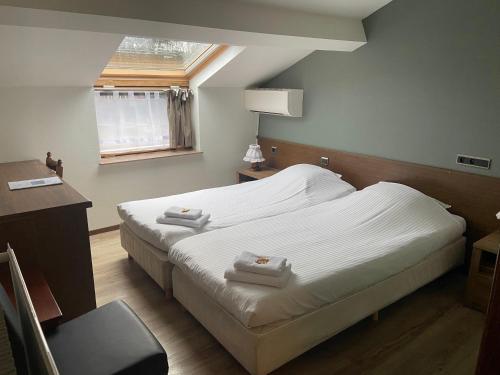聚滕达尔Hotel Monika的一间卧室设有两张床、一张桌子和一个窗口。