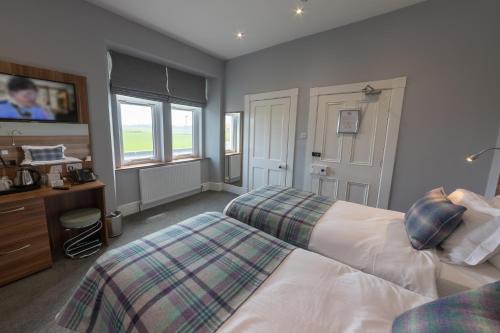 DunnetNorthern Sands Hotel的一间卧室设有两张床、一张桌子和窗户。