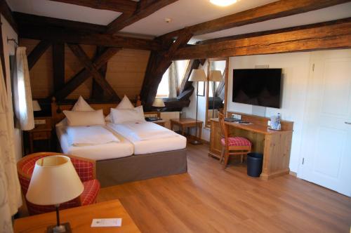 拜尔恩格里斯Metzgerei Gasthof Romantik Hotel Der Millipp的一间卧室配有一张床、一张书桌和一台电视