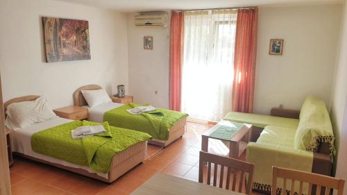 贝西奇Guesthouse Tri Palme的客房设有两张床、一张桌子和一张沙发。