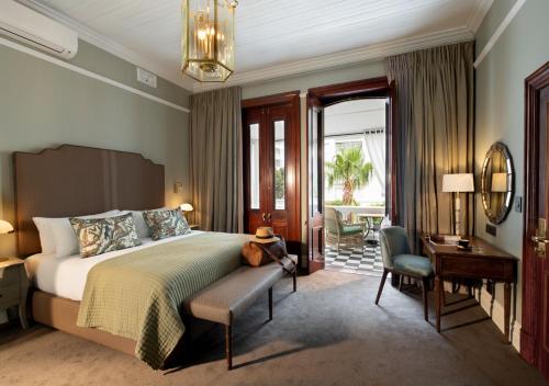 开普敦The Winchester Hotel by NEWMARK的一间卧室配有一张床、一张桌子和一把椅子