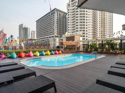 曼谷VELA Dhi GLOW Pratunam的一座游泳池,旁边是一座城市,里面设有色彩缤纷的枕头