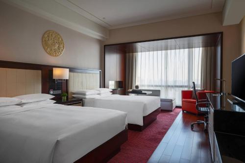 北京北京富力万丽酒店的酒店客房设有两张床和大窗户。