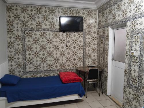 突尼斯Hotel Marhaba - Beb Bhar Tunis的一间卧室配有一张床、一张桌子和一台电视。