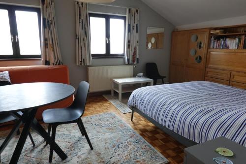 马塞克Logeren in Aldeneik的卧室配有一张床和一张桌子及椅子