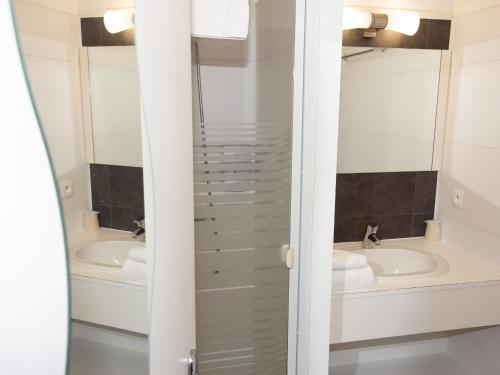 圣马丁德弗莱Cit'Hotel Les Eleis的浴室设有2个水槽和2面镜子