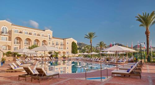 拉曼加戴尔马尔梅纳Grand Hyatt La Manga Club Golf & Spa的一个带椅子和遮阳伞的游泳池的度假酒店