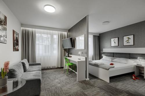 什切青Jantar Resort的一间卧室配有一张床、一张桌子和一张沙发