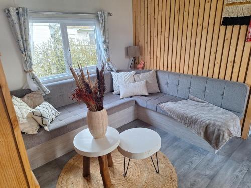 劳雷尔苏格EnJoy Meer und See Ferienhaus -Aan het Lauwersmeer in Lauwersoog -3 Slaapkamers - 1 tot 6 pers -Vanaf 14u al inchecken! Free WIFI!的客厅配有沙发和2张桌子