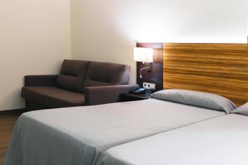 埃尔切埃尔切港酒店的配有一张床和一把椅子的酒店客房