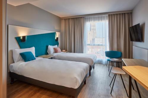 海德堡Aparthotel Adagio Heidelberg的酒店客房配有两张床和一张书桌