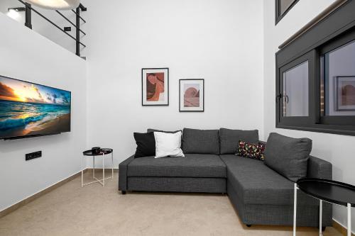 阿斯格罗San Marino Luxury Suites #2的客厅配有白色墙壁上的灰色沙发