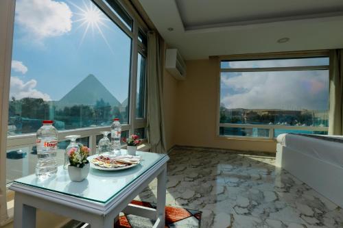开罗Turquoise Pyramids & Grand Egyptian museum view Hotel的客房设有桌子和大窗户。
