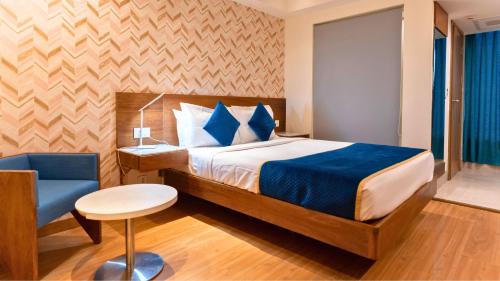 新德里The Orion Plaza - Nehru Place的一间卧室配有一张床和一张蓝色椅子