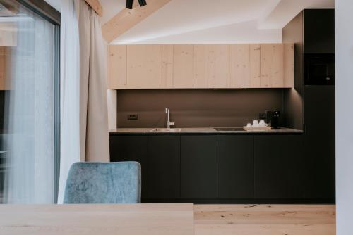 圣维吉利奥Garni Residence Alnö - Adults Only的厨房配有黑色橱柜和蓝色椅子