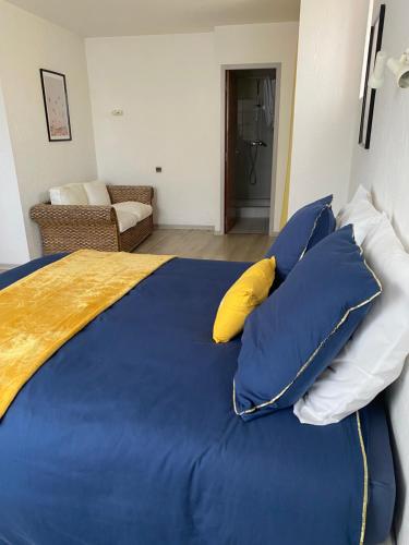 PoueyferréL' Auberge Campagnarde, Lourdes的一张大床,配有蓝色床单和黄色枕头