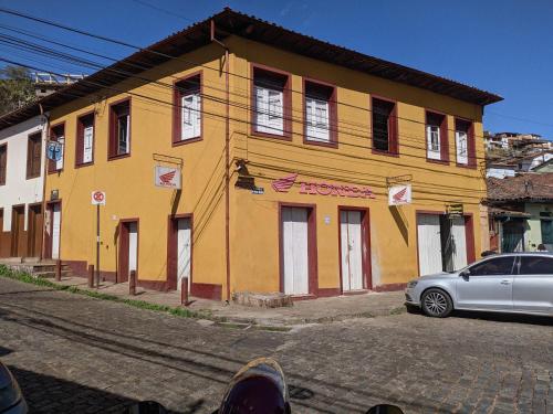 欧鲁普雷图Quarto inteiro, próx ao Centro - República Saideira的一座黄色的建筑,前面有一辆汽车
