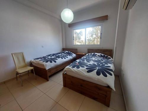 拉纳卡Sunny 2 Bedroom Larnaca Center的配有2张床的带窗户和椅子的客房