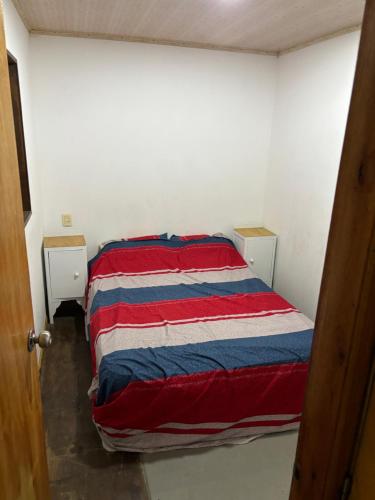 弗赖本托斯Casa roja的一张位于一间红色白色和蓝色毯子的房间里的床