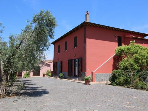 蒙塔尔托迪卡斯特罗Chic Farmhouse in Montalto di Castro with Terrace的前面有棵树的红色建筑