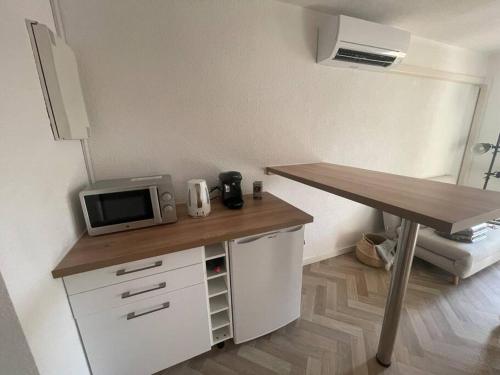 阿格德角Appartement Cap d'Agde dans résidence avec piscine的厨房配有书桌、微波炉和桌子