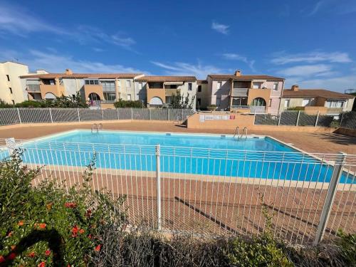 阿格德角Appartement Cap d'Agde dans résidence avec piscine的一个带围栏的游泳池,部分房屋