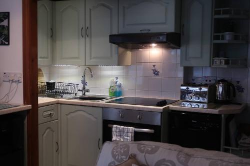 鲍内斯温德米尔Cosy 2-bedroom cottage in the Lake District的厨房配有白色橱柜和炉灶烤箱。