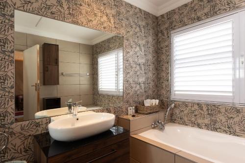 乔治Owls Nest Self Catering的一间带水槽、浴缸和镜子的浴室