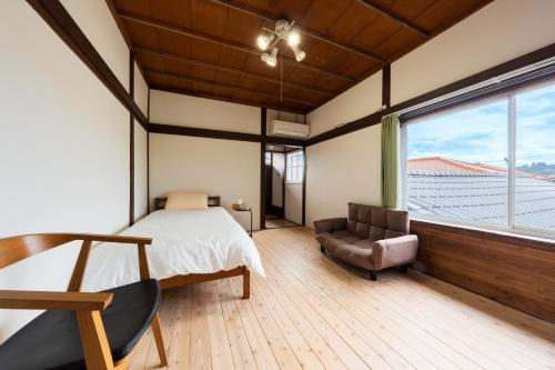 日田市東のおうち的卧室配有床、椅子和窗户。
