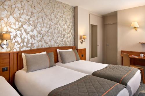 巴黎提姆巴纳斯峰酒店的酒店客房设有两张床,墙上挂有绘画作品