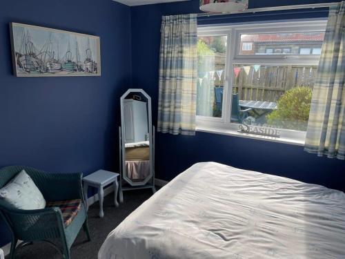 斯泰兹LetAway - Tom's Cabin, Staithes的一间拥有蓝色墙壁的卧室、一张床和窗户