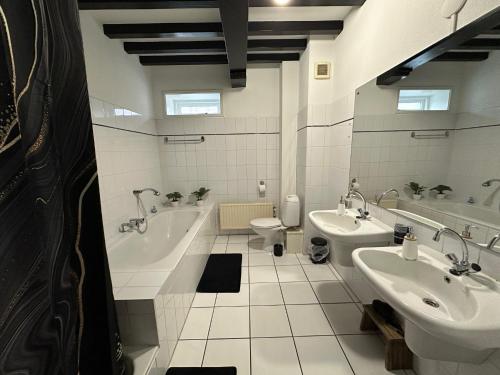 弗利辛恩克莱恩纳世界住宿加早餐旅馆的一间带两个盥洗盆、浴缸和卫生间的浴室