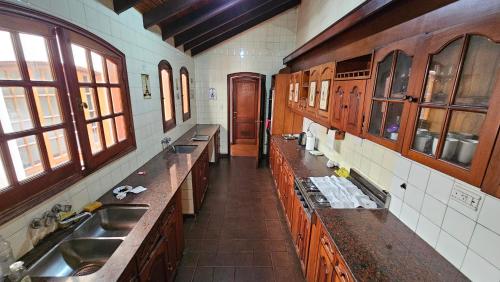 萨尔塔Valhalla Hostel & Suites的大型厨房设有木制橱柜、水槽和窗户。