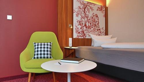 莱茵河畔因格尔海姆英格尔海姆IBB酒店的一间卧室配有一张床、一张绿色椅子和一张桌子