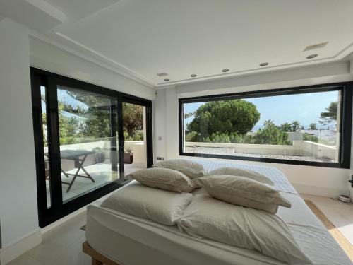 圣埃乌拉利亚Preciosa Villa en Siesta的一间卧室设有大窗户和一张带枕头的床