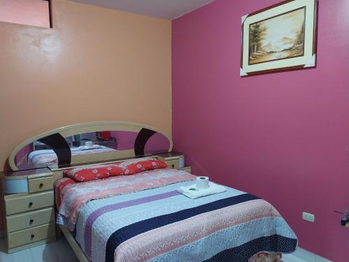 莫约班巴D202的一间卧室配有一张床和粉红色的墙壁