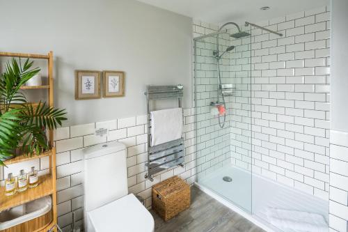 伦敦Contemporary 5 Bedroom with Garden North Finchley的浴室配有白色瓷砖淋浴和浴缸。