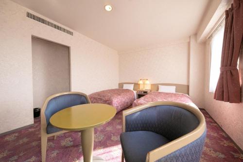 都城市Main Hotel - Vacation STAY 85409v的酒店客房带两张床和一张桌子以及椅子。