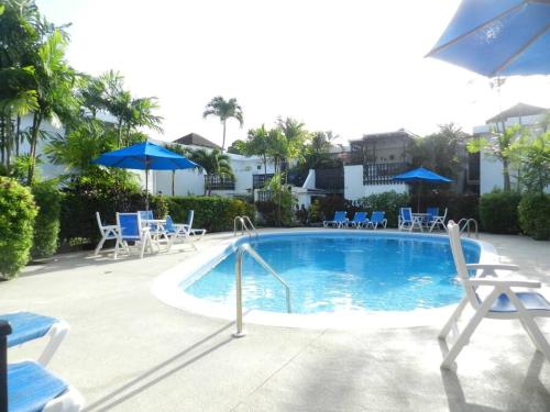 布里奇敦Studio apartment in heart of south coast Barbados的一个带椅子和遮阳伞的大型游泳池