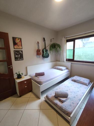 伊达贾伊Quarto Felicidade Cabeçudas的卧室配有两张床,墙上有两把吉他