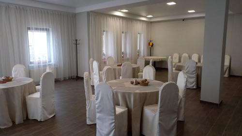 RezinaPensiunea turistică MUZE的一间设有桌椅和白色桌布的房间