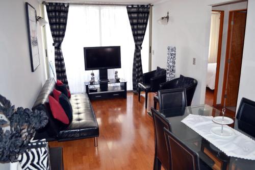 安托法加斯塔阿莫布拉多斯拉赫尔曼达迪公寓的客厅配有黑色皮革家具和平面电视