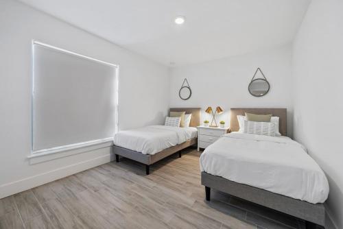西棕榈滩New! Few Minutes To Downtown, 10 To The Beach!的卧室设有两张床,拥有白色的墙壁和木地板